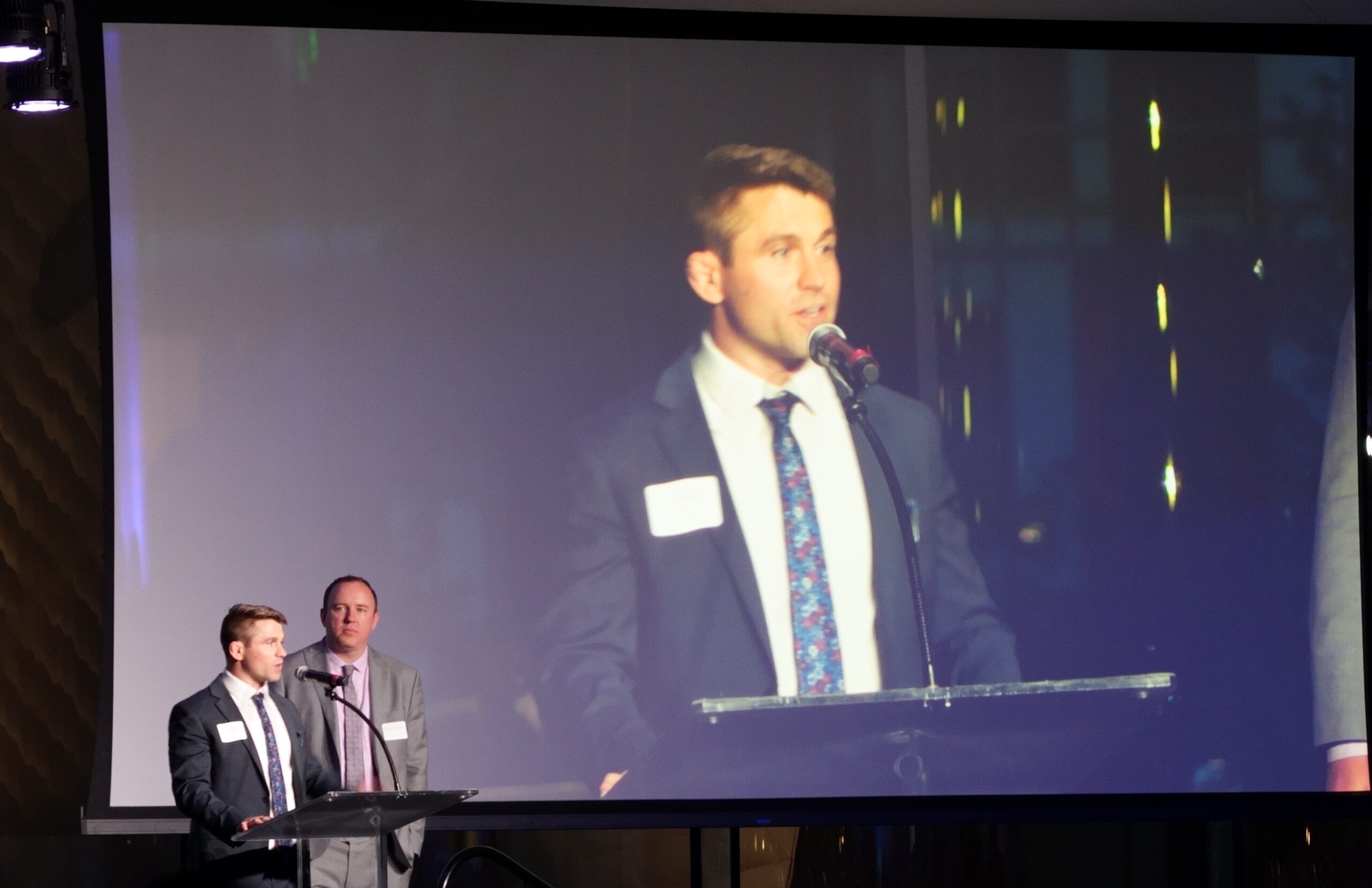 Tim Ganuzzi speaks to the crowd after him and Kevin Cheney, also pictured, received New Trial Lawyer of the Year Award. 