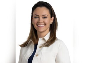 Joanie Donahue smiles at the camera in a professional headshot photo, wearing a white jacket.