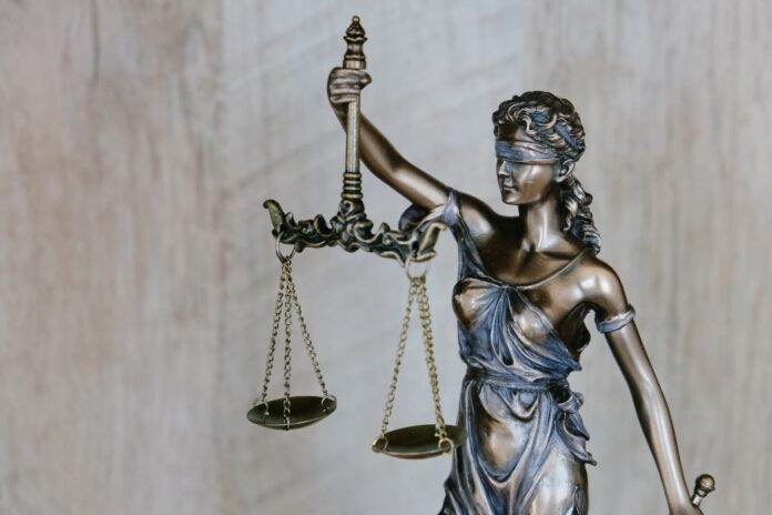 lady justice holds her scales aloft while her sword dangles loosely at her side.