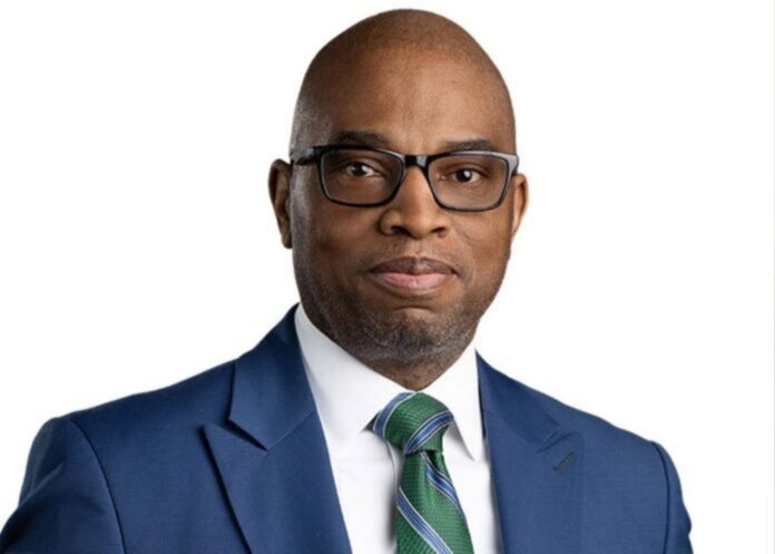 A headshot of Terrance Carroll, wearing a blue suit and green tie.