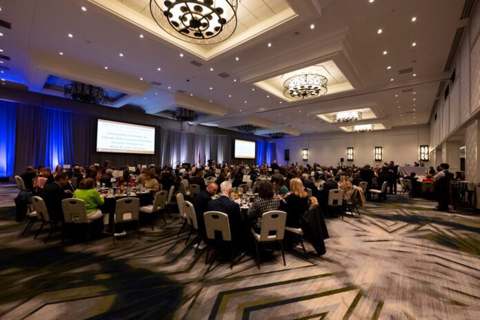 Gala dinner attendees sit at tables in a large ballroom at the Sheraton Downtown